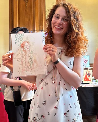 Glückliche Kundin hält ihr Aquarell Portrait in die Kamera