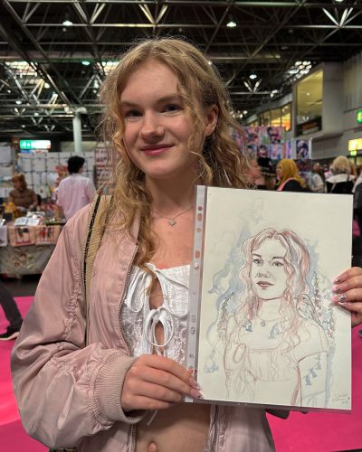 Mädchen hält ihr Aquarell Portrait glücklich in der Hand.